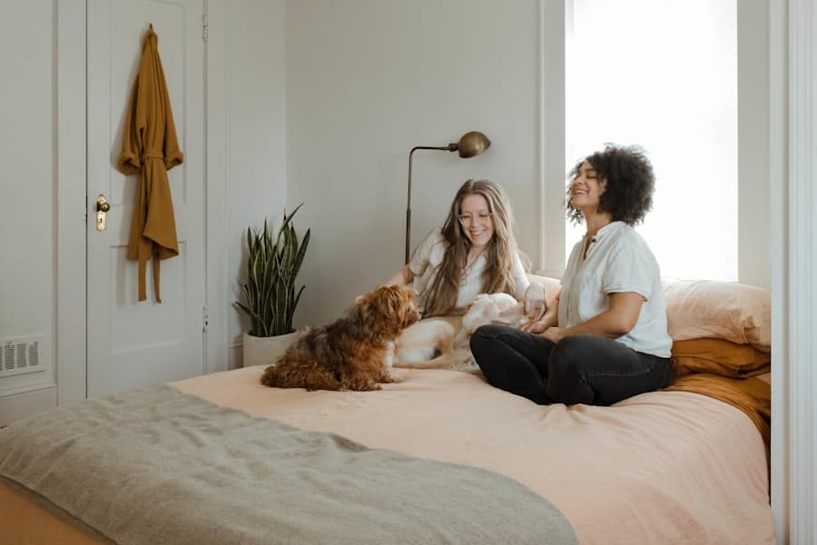 Two people sitting on a bed at home with their dogs